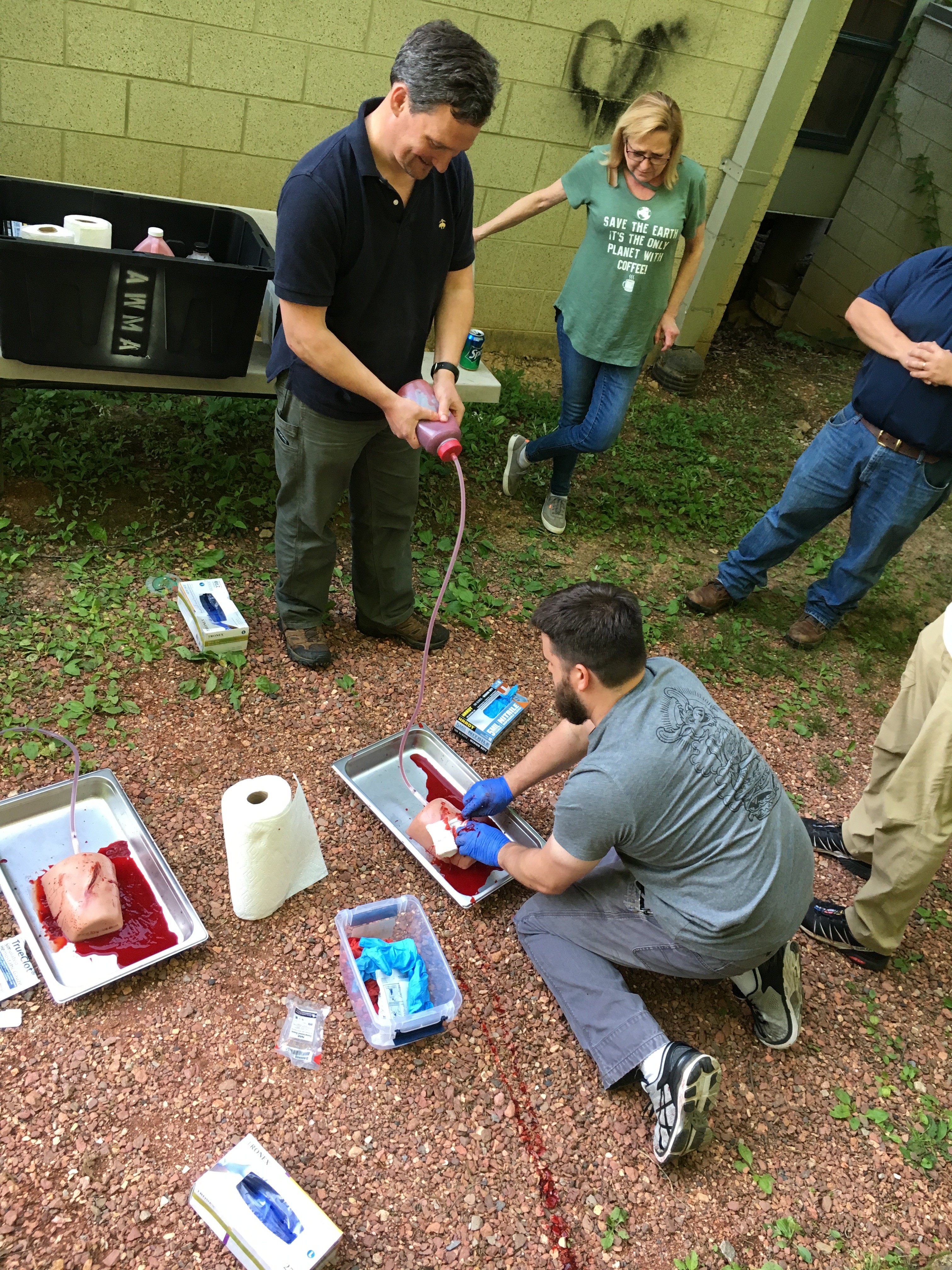 Stephen Gaffin packs a gunshot wound while Lee Burnett pumps the fake blood and Anne Balch looks on.