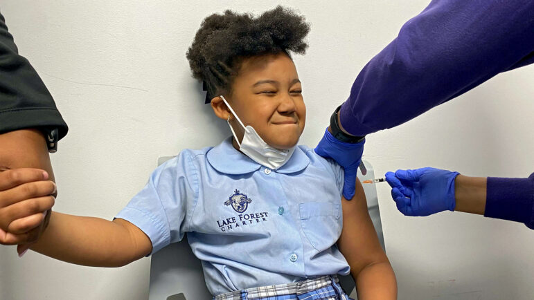 Morgan, 7, holds her mother's hand and winces as she receives the COVID-19 vaccine in her left arm at New Orleans' Crescent Care.