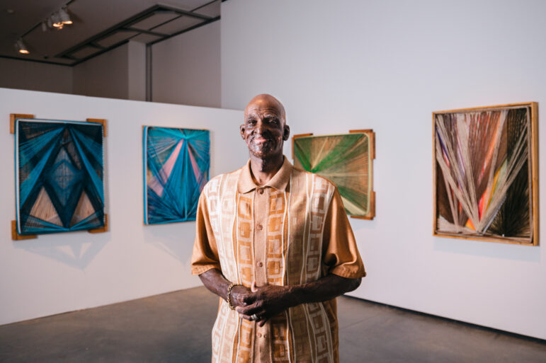 Delrico Gibson poses in front of his artwork at UAB’s Abroms-Engel Institute for Visual Arts.