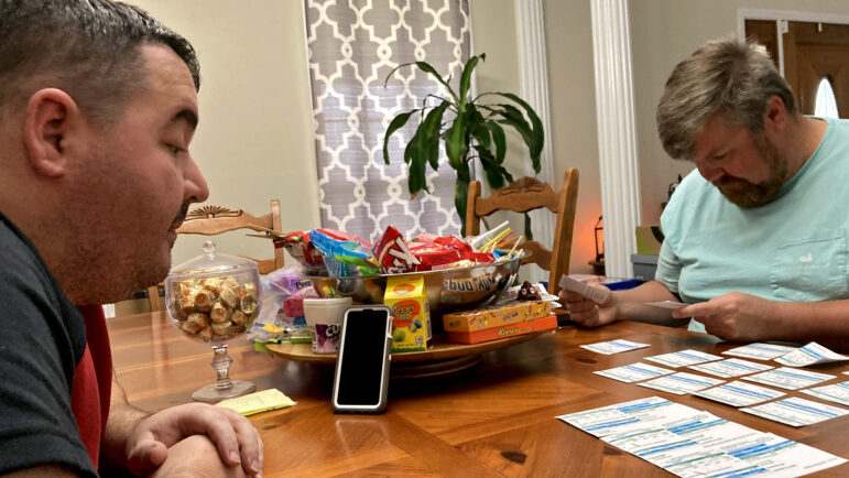 (From left) Jason Clayton and Miles Mason, look over their water bills in Clayton’s home in Lookout Mountain, Alabama, on April 21, 2023.