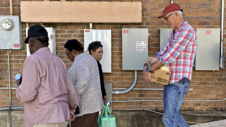 Volunteers carry boxes of food to cars at the Broadmoor Improvement Association’s food pantry in New Orleans, on Dec. 6, 2023.