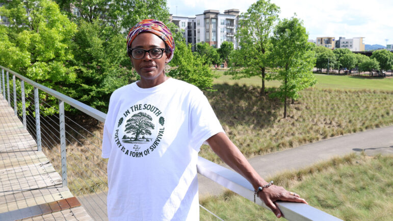 A female poet poses on a bridge in Railroad Park.