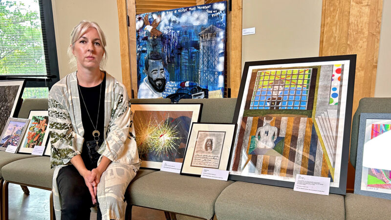 Dr. Katie Owens-Murphy sits with art submitted for the "The Art of Resistance: Documenting Alabama's Death Row" exhibit at the Unitarian Universalist Church of Birmingham on July 21, 2024.