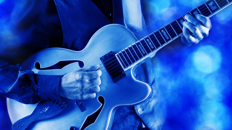 jazz guitarist playing guitar live on stage under blue light