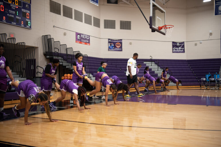 The A.H. Parker High School girls basketball team performs one of Coach O’s unorthodox workouts where girls hold another player's left leg and keep their right leg straight while they walk on their hands during a training session on Nov. 20, 2024.