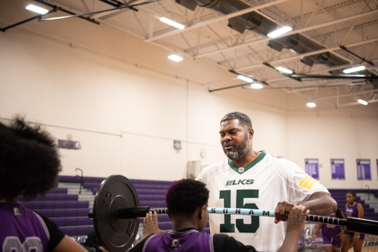 Coach O helps an A.H. Parker athlete with a barbell squat crawl during a training session with the school’s girls basketball team on November 20, 2024.