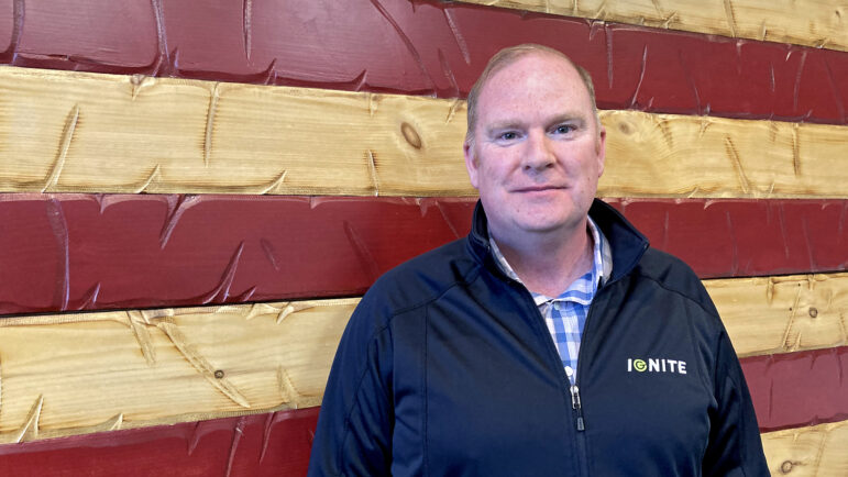 Robert Hamiltion, senior vice president at Ignite in Huntsville, stands before a wooden American flag in Ignite’s office on Jan. 24, 2025.