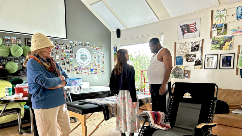 A massage therapist (center) speaks to a resident (right) at Bastion, a veterans community in New Orleans, on Jan. 17, 2025.