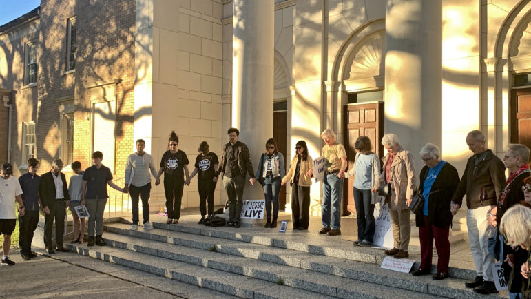 People gathered on the steps of First Grace United Methodist Church in New Orleans hold hands and say a prayer during a vigil for Jessie Hoffman on Tuesday, March 18, 2025. 