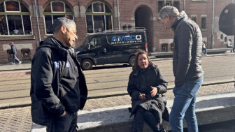 GGD social worker Mohamed Bakayan (left) and Dutch police officer Bob Blankenzee (right) talk with a woman drinking from a bottle of wine on a bench in Amsterdam, Netherlands on Tuesday, March 11, 2025.