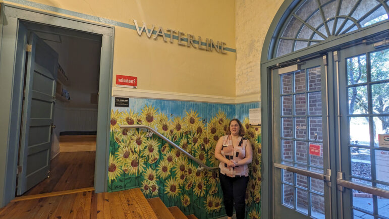 Claire Gray, the museum’s assistant director, stands beneath the water line in the museum showing how high water levels were during the storm.
