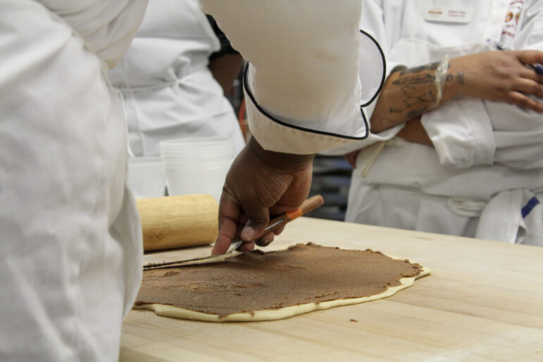 Reddick demonstrates how to spread the filling by pushing it with an offset spatula to avoid tearing the dough.